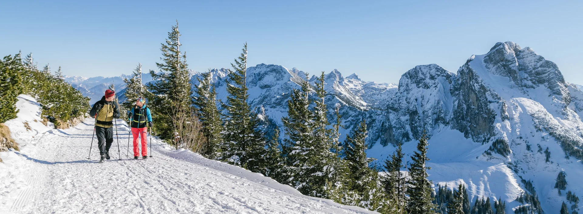 Zwei Wanderer auf winterlichen Wegen mit einer tollen Bergkulisse.