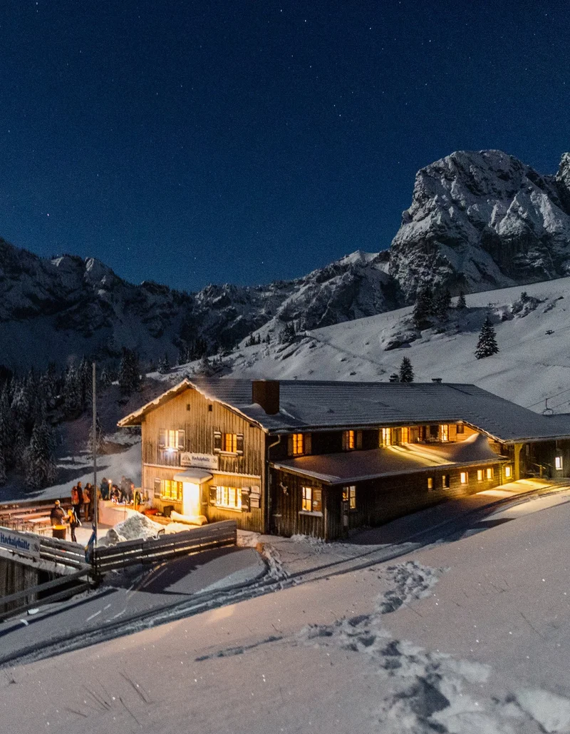 Hochalphütte bei Nacht auf dem Breitenberg Die Hochalphütte in Pfronten in einer idyllisch verschneiten Landschaft und magischen Beleuchtungen bei Nacht.