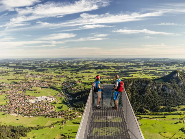 Weitreichender Blick über den Aussichtssteg auf dem Breitenberg auf das Pfrontener Tal und die umliegende Berglandschaft.