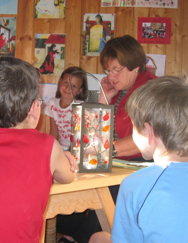 Märchen- und Malstunde im Märchenstadel Eine Gruppe Kinder sitzt um einen Tisch bei einer Märchen- und Malstunde.
