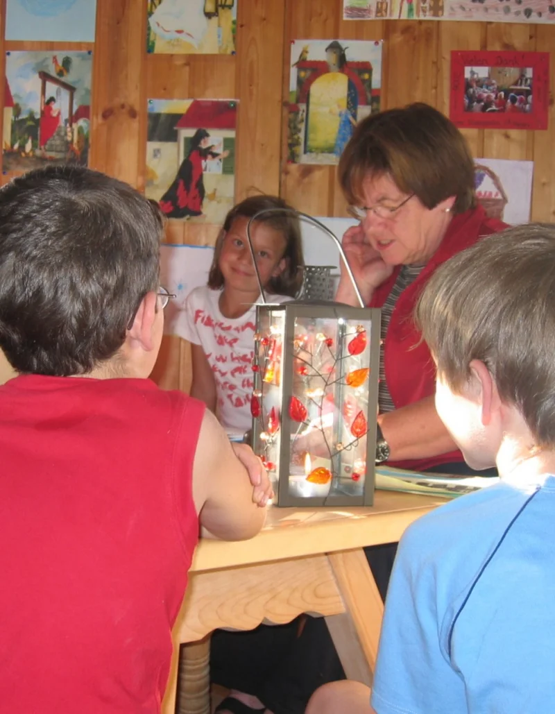 Märchen- und Malstunde im Märchenstadel Eine Gruppe Kinder sitzt um einen Tisch bei einer Märchen- und Malstunde.