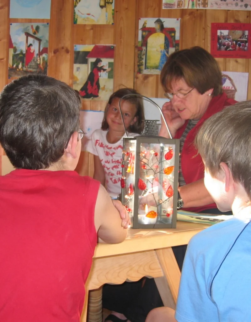 Märchen- und Malstunde im Märchenstadel Eine Gruppe Kinder sitzt um einen Tisch bei einer Märchen- und Malstunde.
