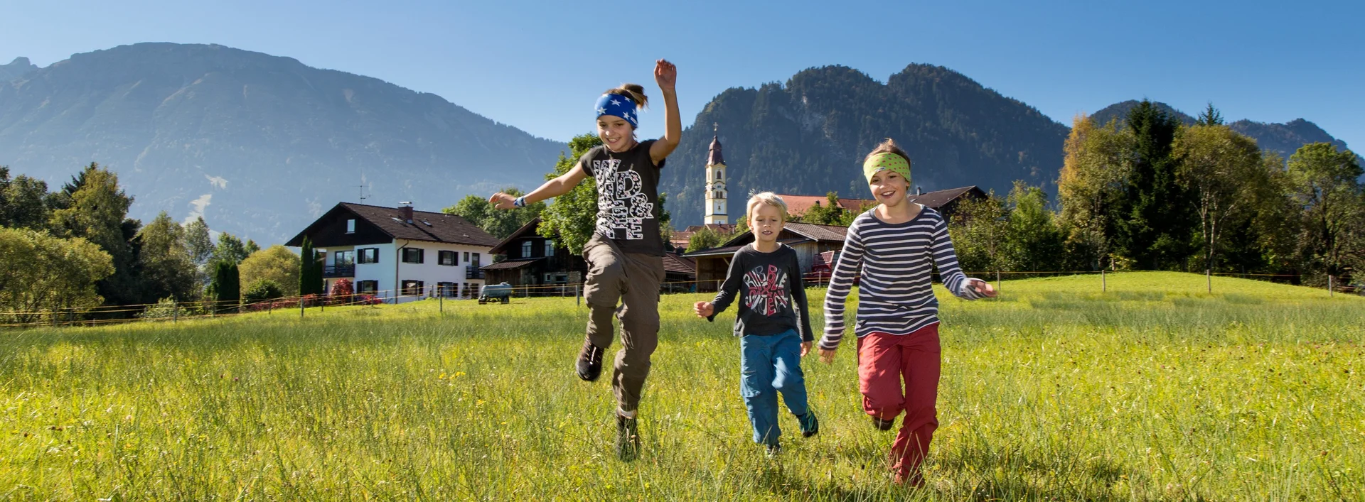 Wandern mit der Familie in Pfronten im Allgäu Kinder rennen auf einer grünen Wiese in Pfronten und haben Spaß.