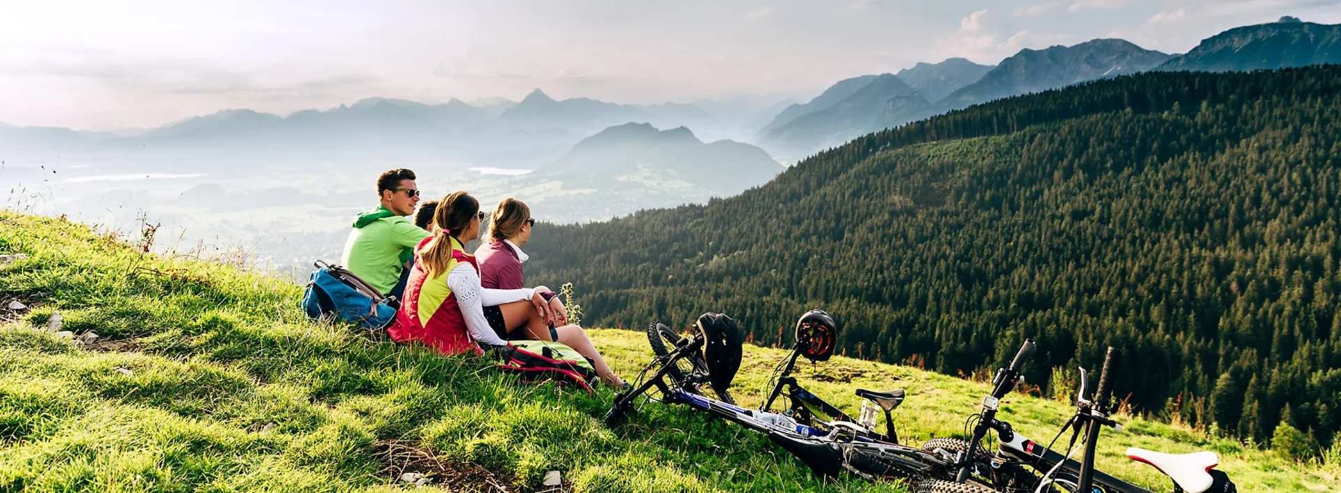 Eine Gruppe Mountainbiker genießt bei einer Pause den Ausblick auf das beeindruckende Bergpanorama.