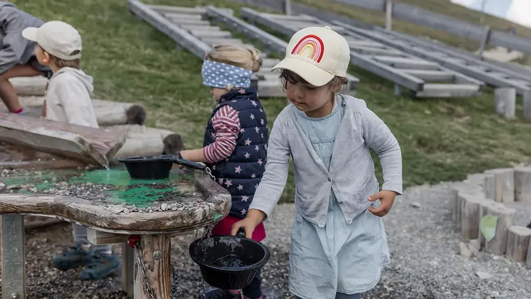 Kinder spielen an einem Wasserspieltisch.