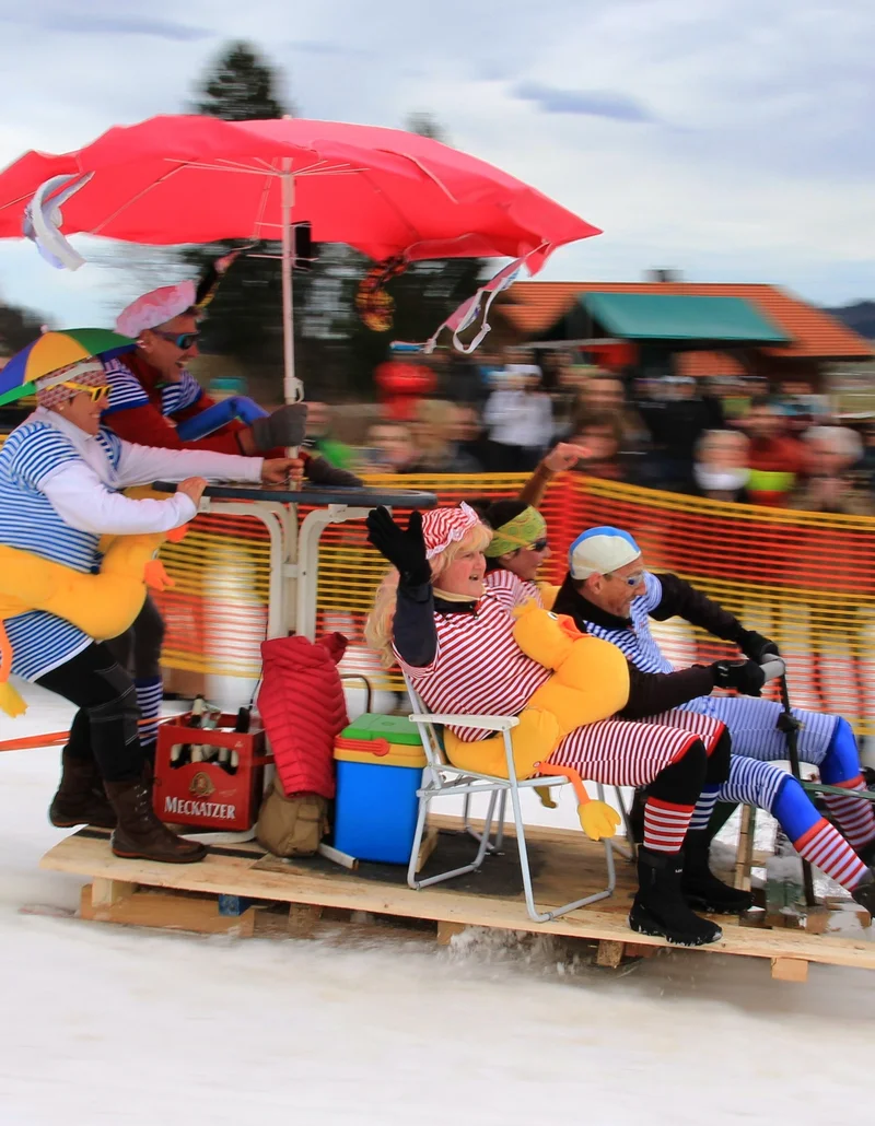 Das Gaudirennen in Pfronten im Allgäu Mehrere Personen auf einem selbstgebauten Schlitten beim Gaudirennen in Pfronten im Allgäu.