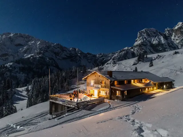 Die Hochalphütte in Pfronten in einer idyllisch verschneiten Landschaft und magischen Beleuchtungen bei Nacht. 