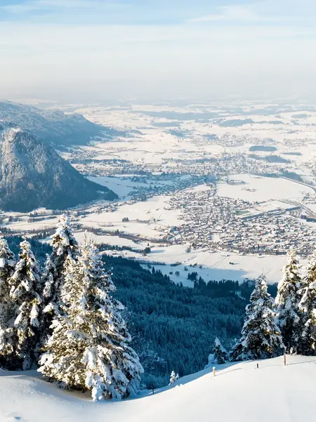 Winterlicher Panoramablick auf das verschneite Pfrontener Tal und die umliegende Berglandschaft.