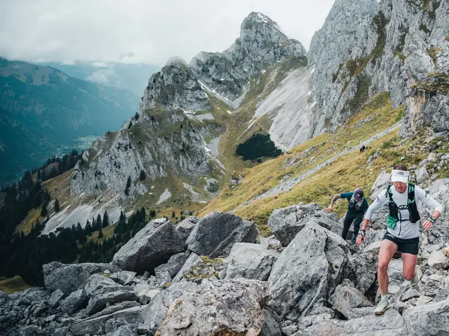 Zwei Trailrunner beim Aufstieg in einer alpinen Bergkulisse.