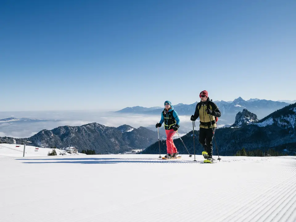 Schneeschuhwanderer in einer sonnigen Winterlandschaft am Breitenberg mit Blick auf die beeindruckende Berglandschaft.