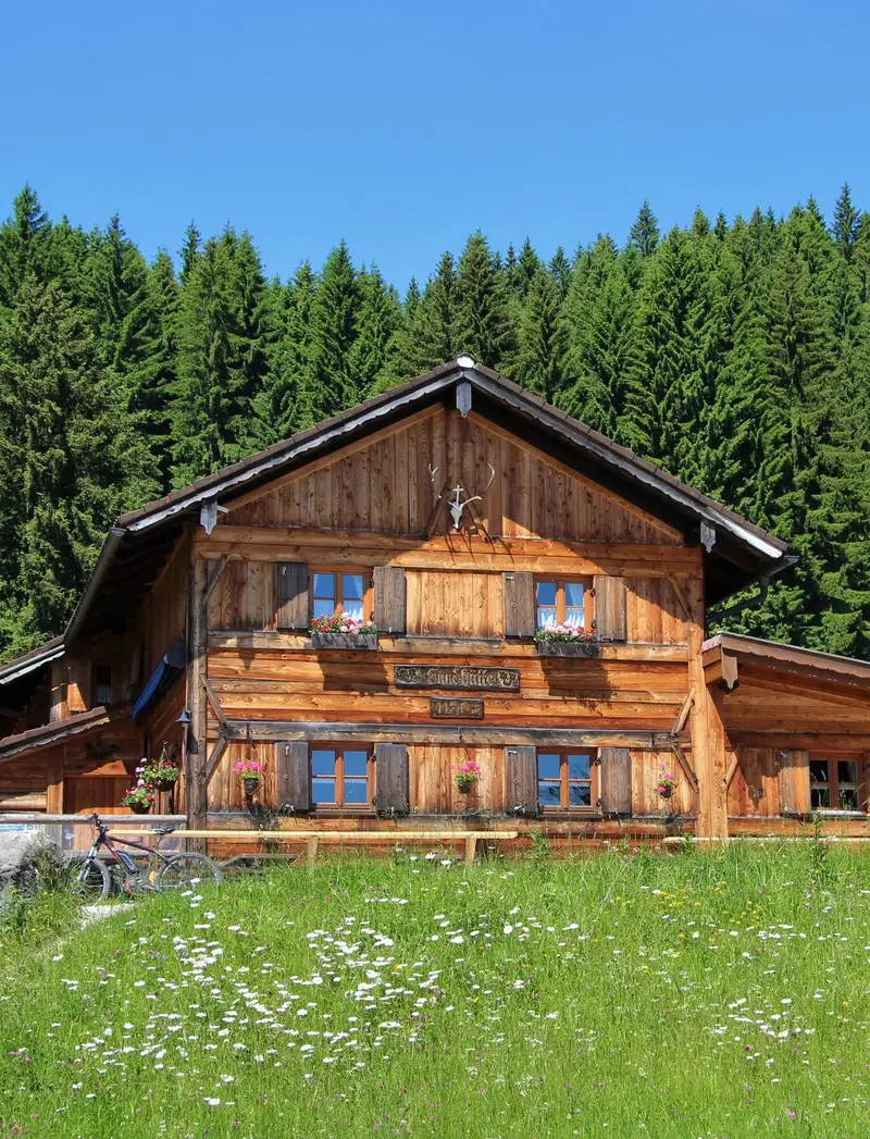 Sommerliche Sicht auf grüne Wiesen und die Edelsberghütte in Pfronten.